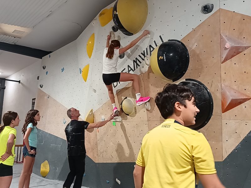 Alumna escalando en el muro de bloque mientras un monitor la acompaña