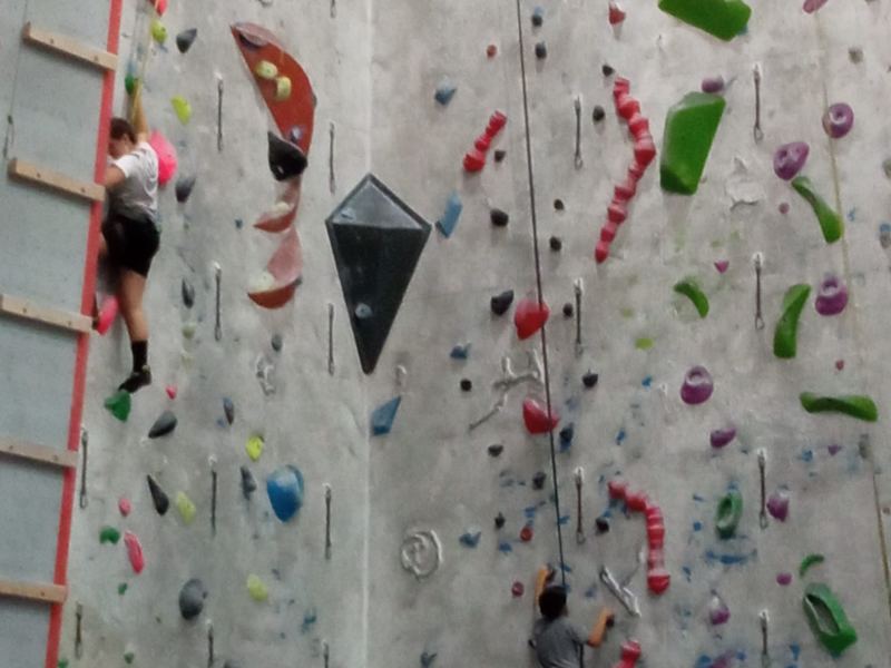 Alumnado equipándose con el arnés para la actividad de escalada