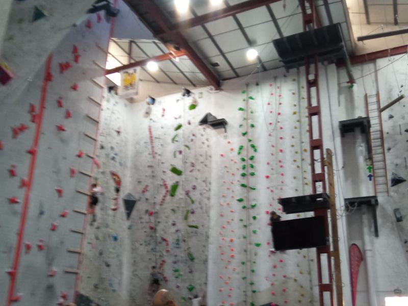Alumna escalando la pared de altura del rocódromo asegurada con cuerda